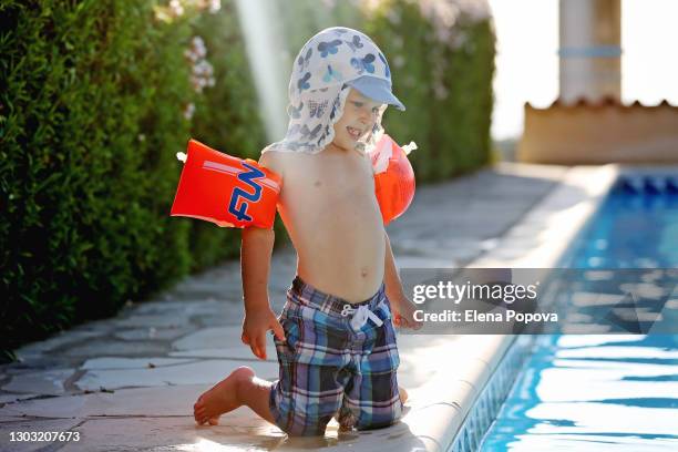 cute boy 2-3 y.o. playing next the swimming pool at summer sunny day - brazaletes acuáticos fotografías e imágenes de stock