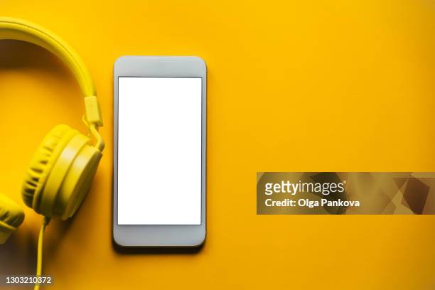 smartphone with empty display next to headphones on a yellow background. mockup, template. podcasting concept. - e learning template stock pictures, royalty-free photos & images