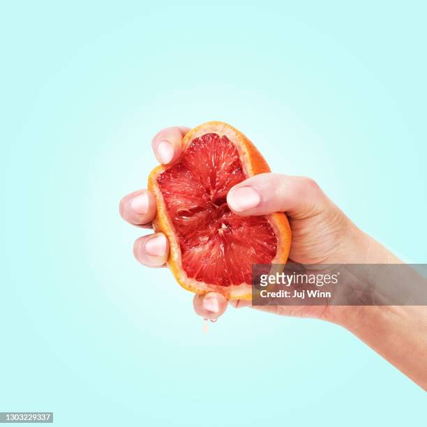 hand squeezing grapefruit - afferrare foto e immagini stock