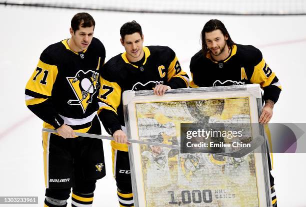 Sidney Crosby of the Pittsburgh Penguins poses with teammates Mike Matheson and Evgeni Malkin to honor Crosby for his 1000th NHL appearance prior to...