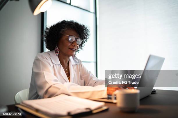 doctor using laptop or doing a telemedicine call with patient - answering email stock pictures, royalty-free photos & images