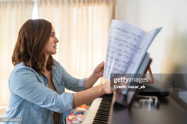 vrouw thuis die pianolessen praktiseert. - edm stockfoto's en -beelden