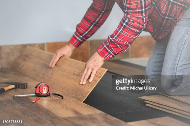 worker hands installing timber laminate floor in the room. imitation wood. - pavimento foto e immagini stock