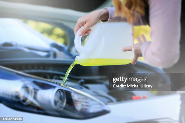 a young woman pouring summer, yellow liquid for washing car screen. - plastic water storage tank stock pictures, royalty-free photos & images