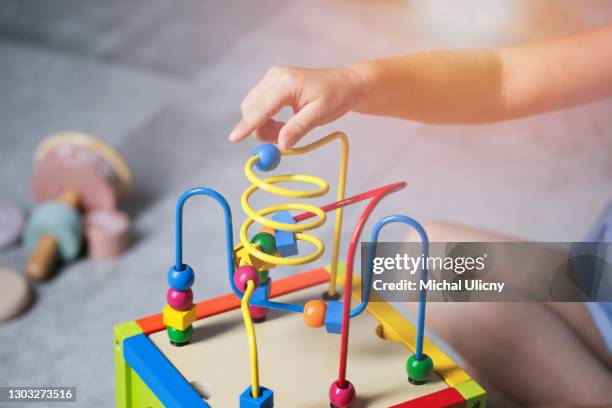 little cute baby is played with a colorful interactive toy, made of wood. - nursery school building stock pictures, royalty-free photos & images