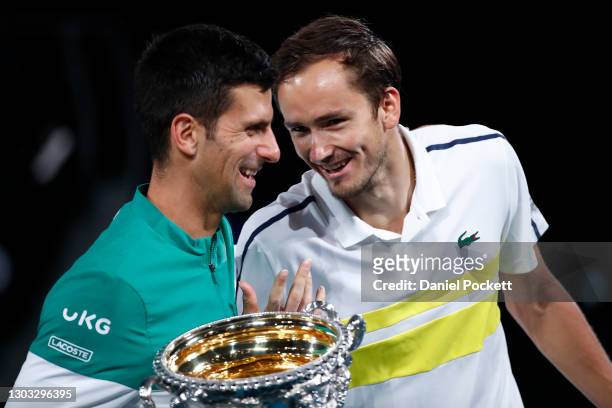 Novak Djokovic of Serbia holds the Norman Brookes Challenge Cup as he shares a joke with opponent Daniil Medvedev of Russia following their Men’s...