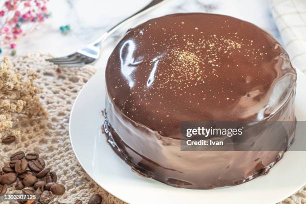 whole chocolate sachertorte cake on table with decoration - sachertorte stock-fotos und bilder