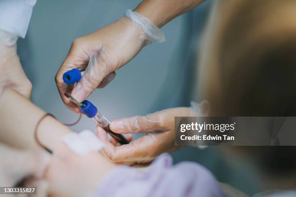 sluit omhoog aziatische chinese verpleegster die bloed van vrouwelijke chinese geduldige wapenader in de kliniek trekt - female nurse stockfoto's en -beelden