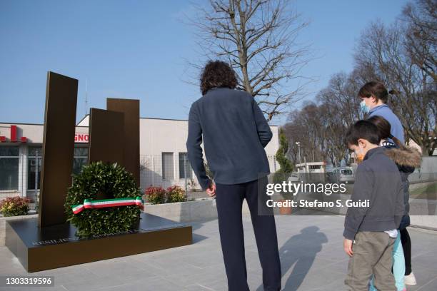 People wearing protective mask look at the memorial for the victims of coronavirus on February 21, 2021 in Codogno, Italy. A memorial for the victims...