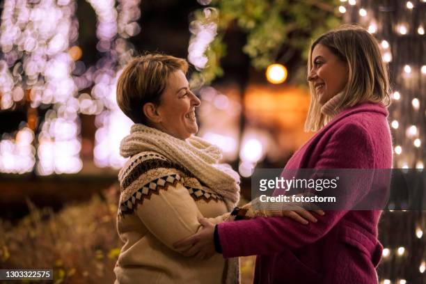 glimlachende moeder en dochter die een bondingmoment bij het park hebben dat voor kerstmis wordt verfraaid - mother and daughter on night street stockfoto's en -beelden