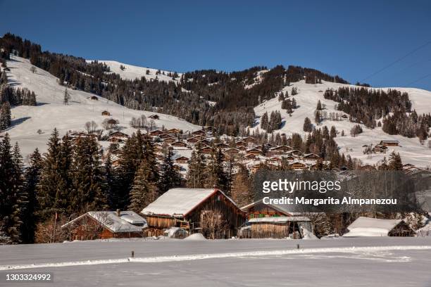 typical swiss alpine landscape with wooden chalets in the snow - gstaad stockfoto's en -beelden
