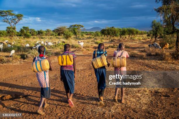 african children carrying water from the well, kenya, east africa - kenya road stock pictures, royalty-free photos & images