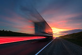 Motion blur. The truck is driving at high speed on the highway. Red Sky.