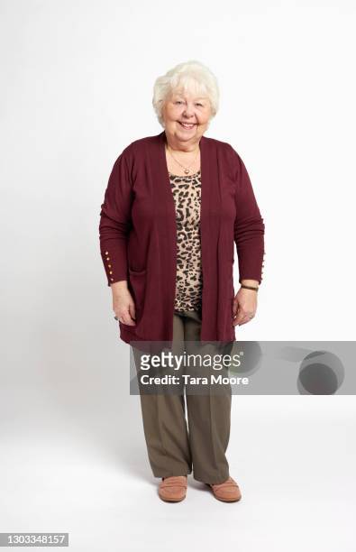 full length of senior woman smiling - seniorin stock-fotos und bilder