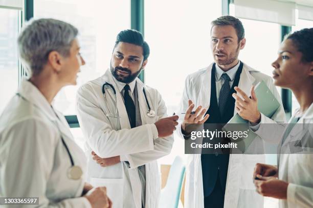 multi-etnische groep artsen die een bespreking hebben - fighting group stockfoto's en -beelden