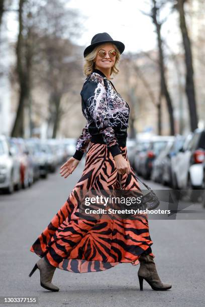 German TV host Carola Ferstl wearing a black hat by Marzi, a vintage long ombre peach colored dress with black zebra print, a black bomber jacket...