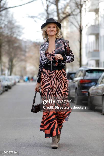 German TV host Carola Ferstl wearing a black hat by Marzi, a vintage long ombre peach colored dress with black zebra print, a black bomber jacket...