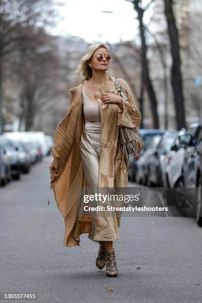 German TV host Carola Ferstl wearing a long gold coat by Nanna Kuckuck, silver sandals by Jimmy Choo, sunglasses by H&M, a beige bag with fringe...