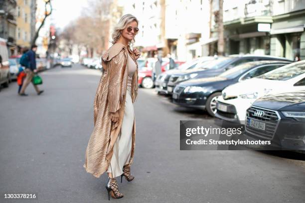 German TV host Carola Ferstl wearing a long gold coat by Nanna Kuckuck, silver sandals by Jimmy Choo, sunglasses by H&M, a beige bag with fringe...