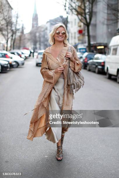 German TV host Carola Ferstl wearing a long gold coat by Nanna Kuckuck, silver sandals by Jimmy Choo, sunglasses by H&M, a beige bag with fringe...