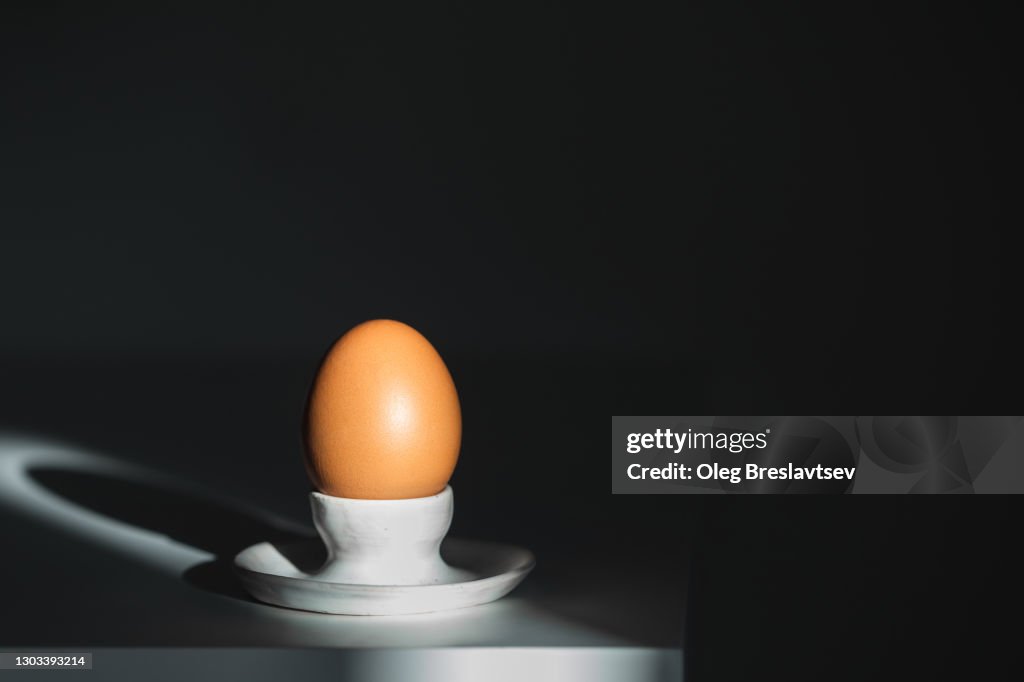 One egg in ceramic egg-Cup holder on dark background with beautiful light