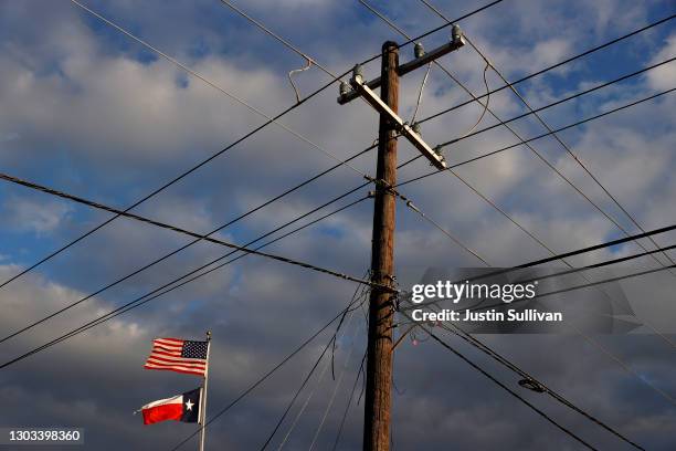 The U.S. And Texas flags fly next to a power pole on February 21, 2021 in Houston, Texas. Millions of Texans lost their power when winter storm Uri...