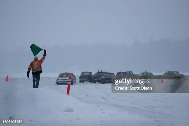 Wagner waves a green flag to start racers driving on the ice at Rice Lake during a snowy day on February 21, 2021 in Rice Lake, Wisconsin. Races are...