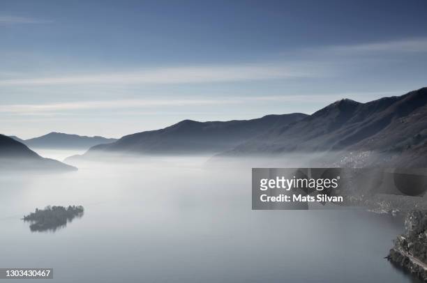 aerial view over brissago islands on a foggy alpine lake maggiore with mountain - アスコナ ストックフォトと画像