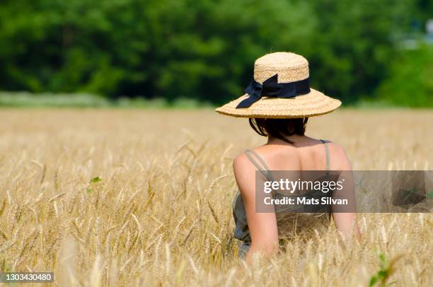 woman with a straw hat standing in a wheat field - tessin stock-fotos und bilder