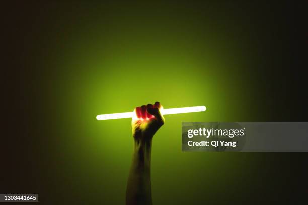 holding a glow stick in the dark - luce fluorescente foto e immagini stock