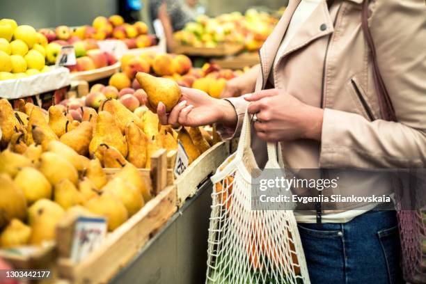 woman choosing fruits at farm market and using reusable eco bag. - pear stock pictures, royalty-free photos & images