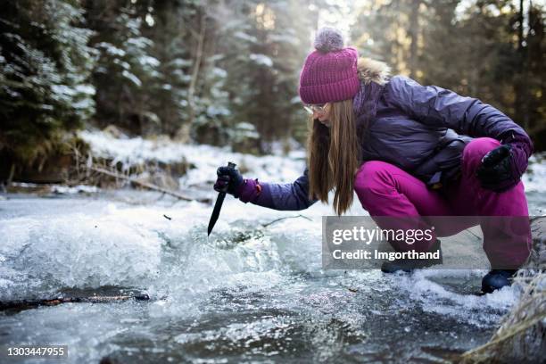 teenage mädchen spielen durch strom im winter - knife splash stock-fotos und bilder