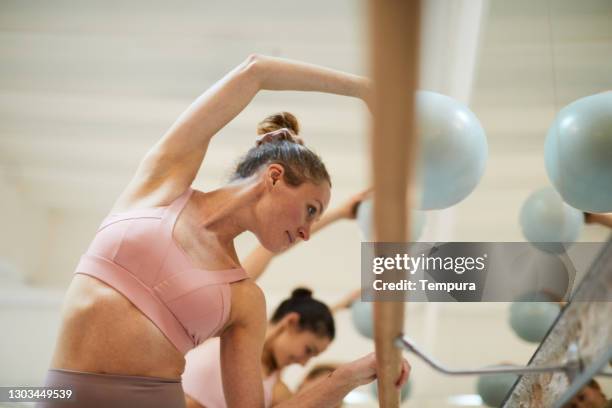 una mujer con una pelota de fitness en una clase de entrenamiento de barre. - dance studio fotografías e imágenes de stock