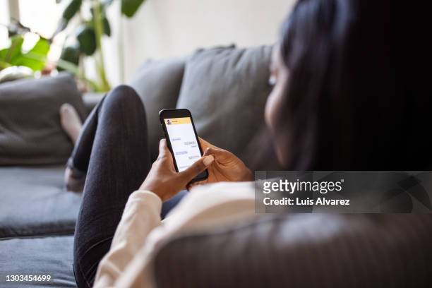 woman at home texting on her mobile phone - aplicación para móviles fotografías e imágenes de stock