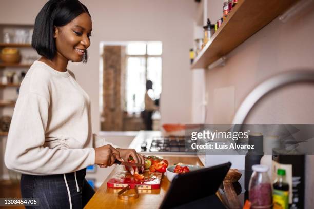 woman video calling friend while cooking - chopping vegetables stock pictures, royalty-free photos & images