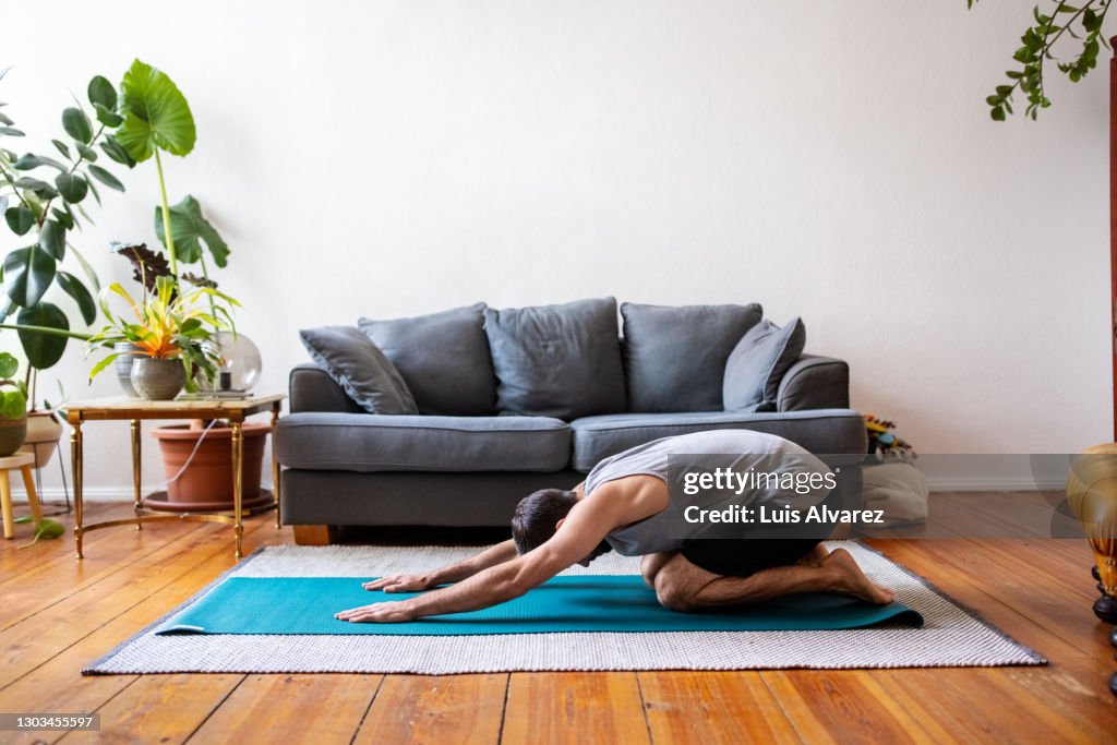 Man in childs pose at home