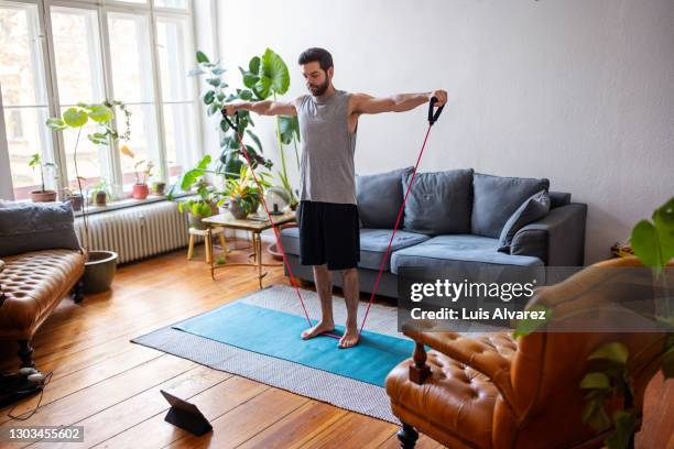 man watching online videos and doing exercise at home - exercício de relaxamento imagens e fotografias de stock