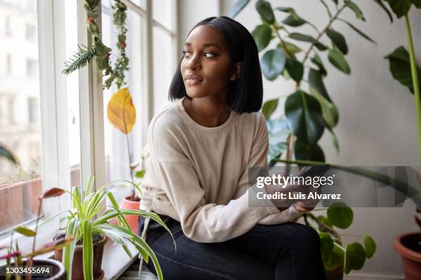 woman at home looking outside window - driekwartlengte stockfoto's en -beelden