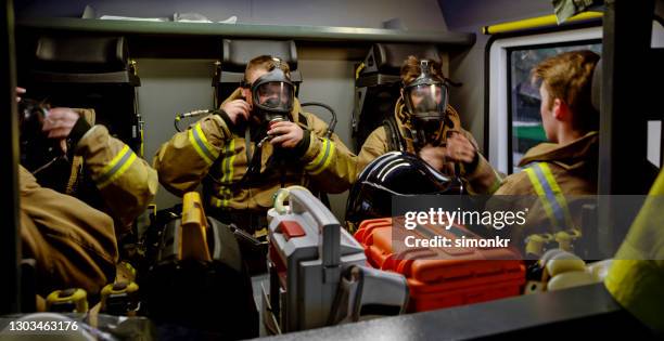 feuerwehrleute sitzen im feuerwehrauto - atemschutz stock-fotos und bilder