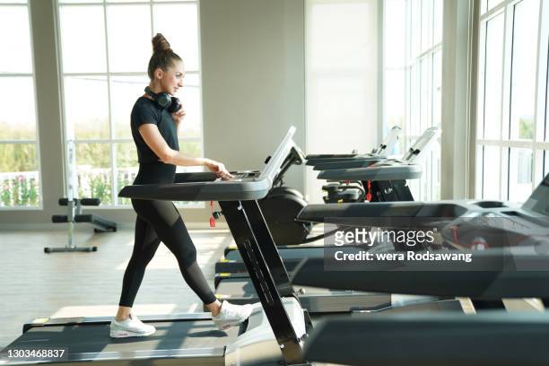young woman with headphone walking exercising on treadmill at gym - warm up exercise indoor stock pictures, royalty-free photos & images