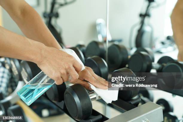 using wet wipe and alcohol spraying cleaning dumbbell equipment - rubbing stock pictures, royalty-free photos & images