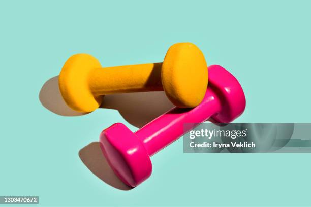 sport lifestyle concept with pink yellow dumbbells on pastel mint green background. - hantel stock-fotos und bilder