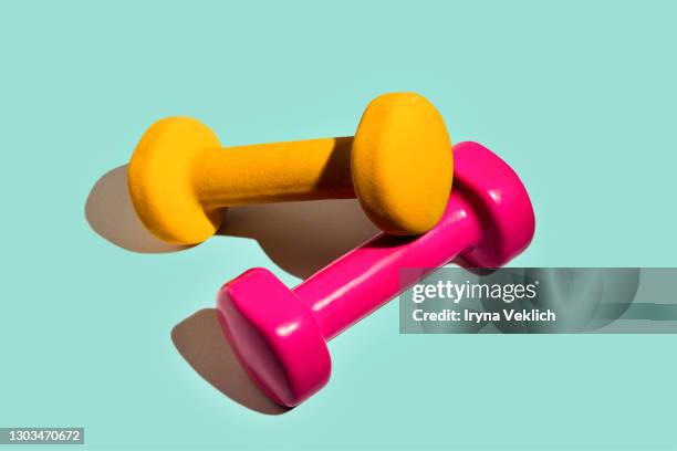 sport lifestyle concept with pink yellow dumbbells on pastel mint green background. - manubrio foto e immagini stock