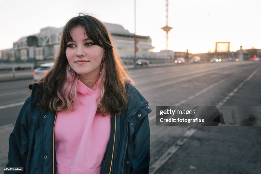 Portrait of a cool teenage girl with pink hoodie, urban background