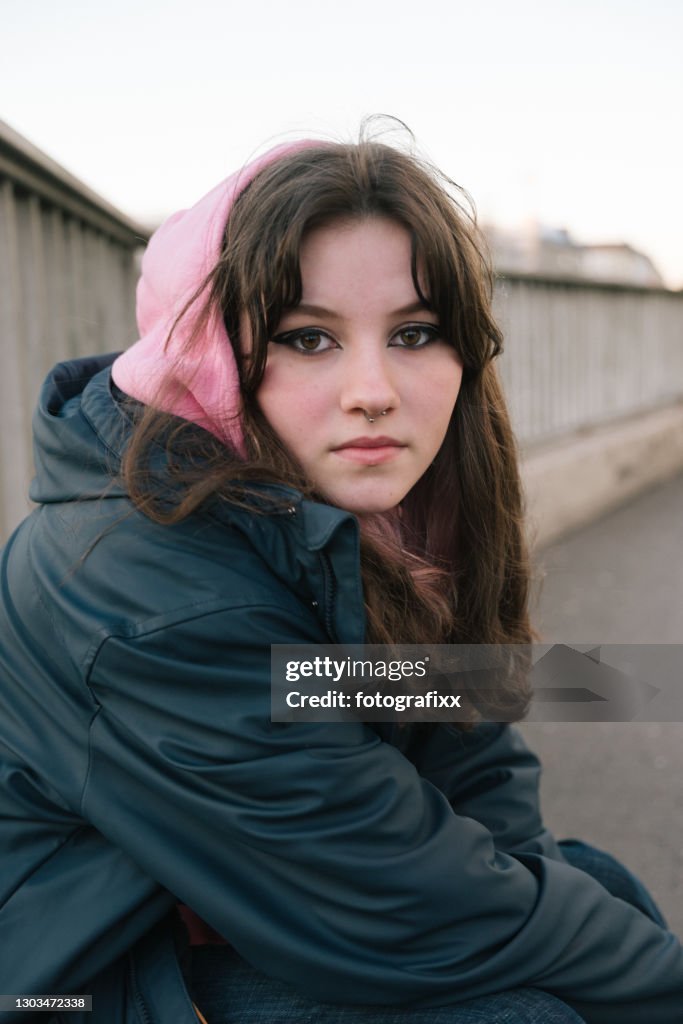 Portrait of a cool teenage girl with pink hoodie, urban background