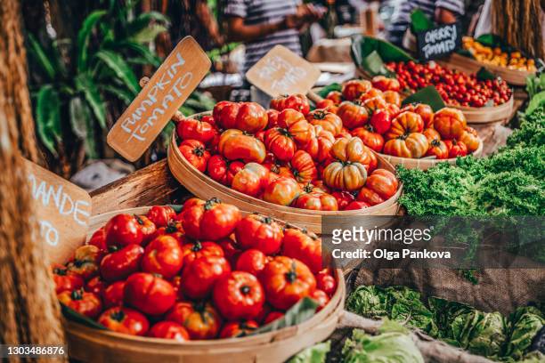 tomatoes and greeny on counter of vegetable market. - mercato di prodotti agricoli foto e immagini stock