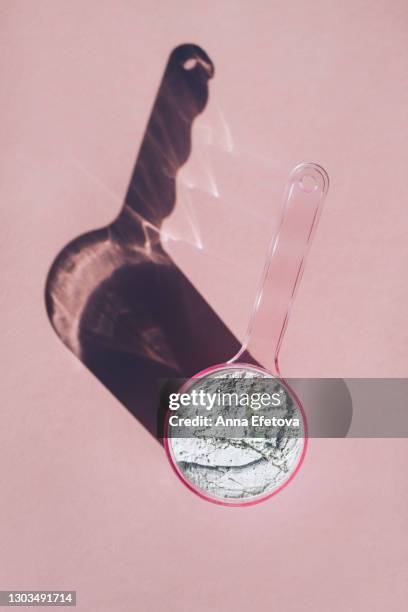 measuring spoon with collagen powder or alginate mask on pink background - eiwit stockfoto's en -beelden