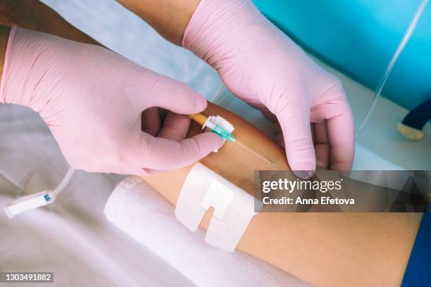 doctor's hands in pink gloves preparing infusion needle for injections - iv infusion stockfoto's en -beelden