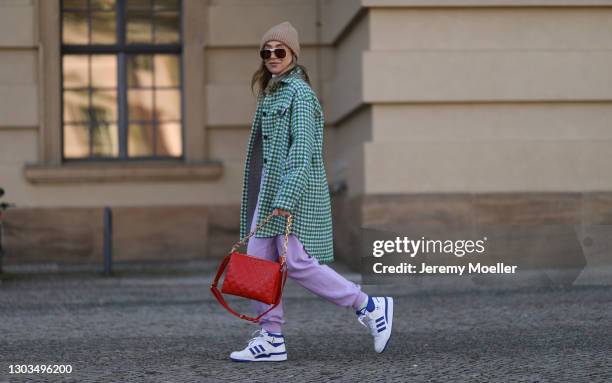 Sonia Lyson wearing Louis Vuitton Coussin red bag, Adidas white and blue Forum84 sneaker, Bottega Veneta shades, Monki lilac joggingpants, Munthe...