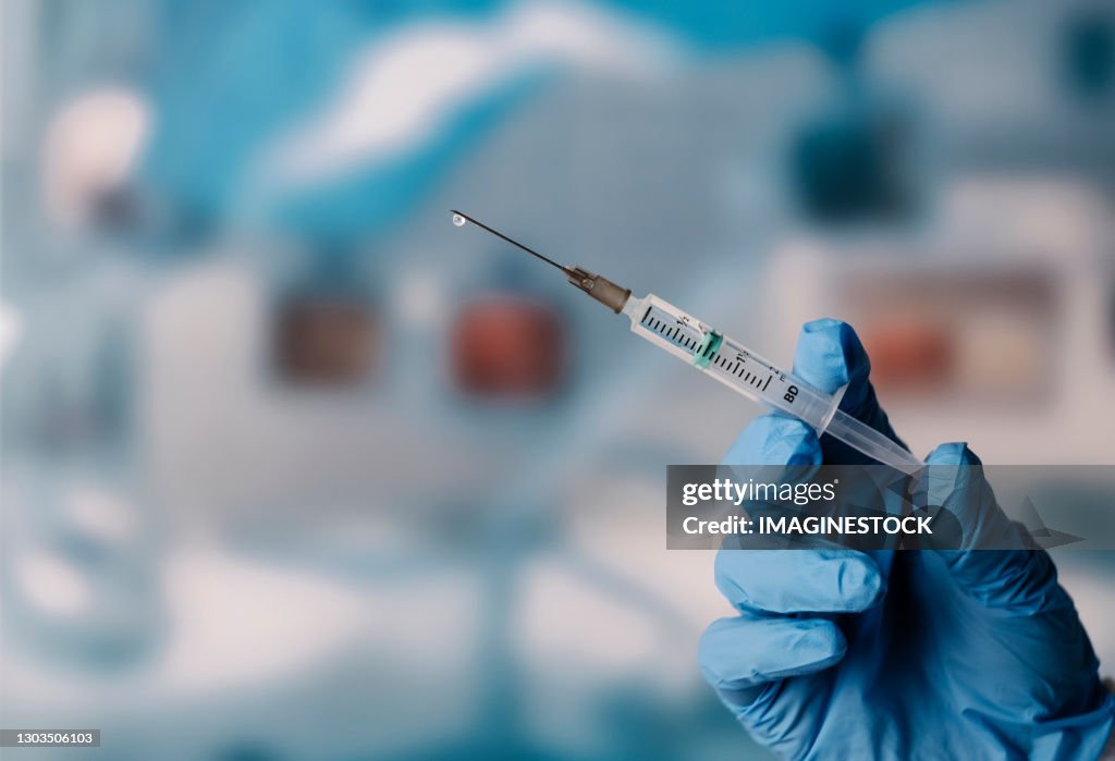 Gloved Hand holding a Syringe